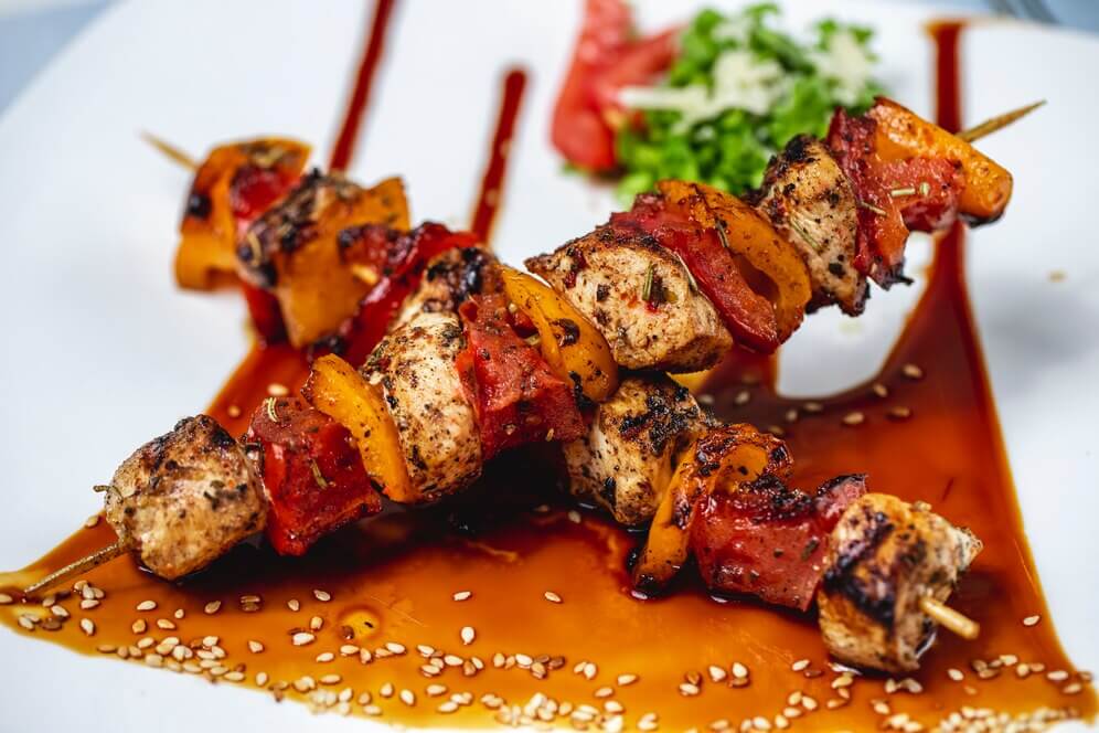 side view chicken skewers grilled chicken fillet with red yellow peppers seasoning sauce sesame seeds plate 141793 4853
